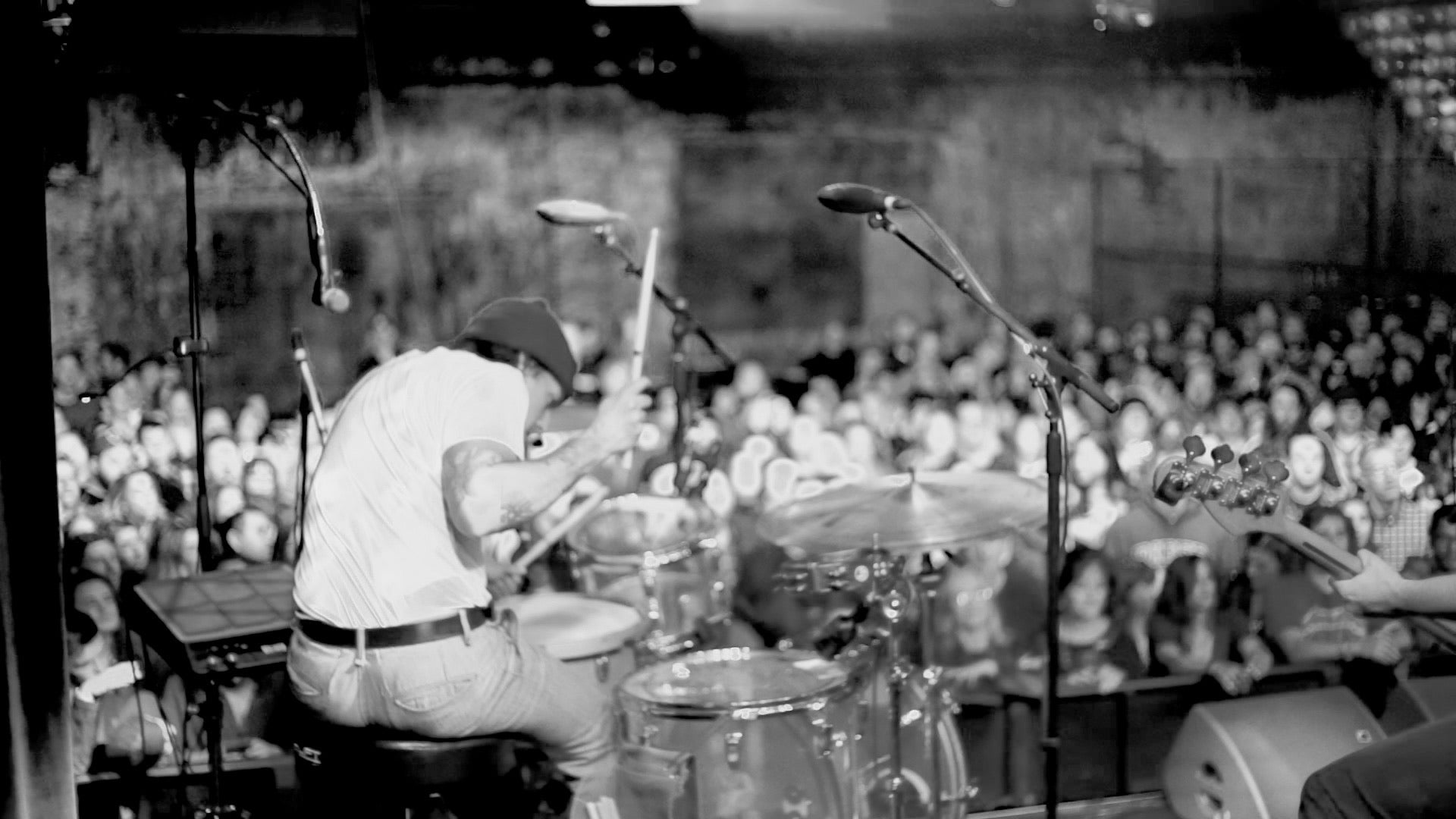 black and white image of drummer with crowd in the background