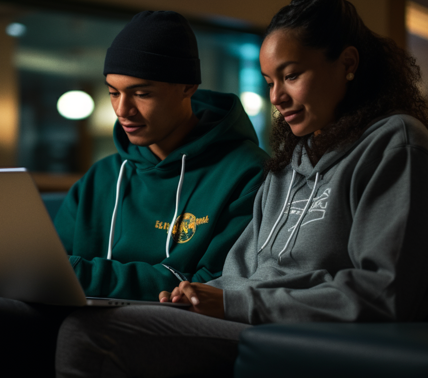 a man and woman wearing custom hoodies sitting together on a couch